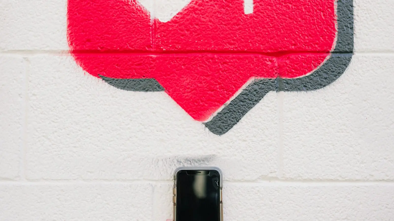 Smartphone in front of a wall painted with a red heart