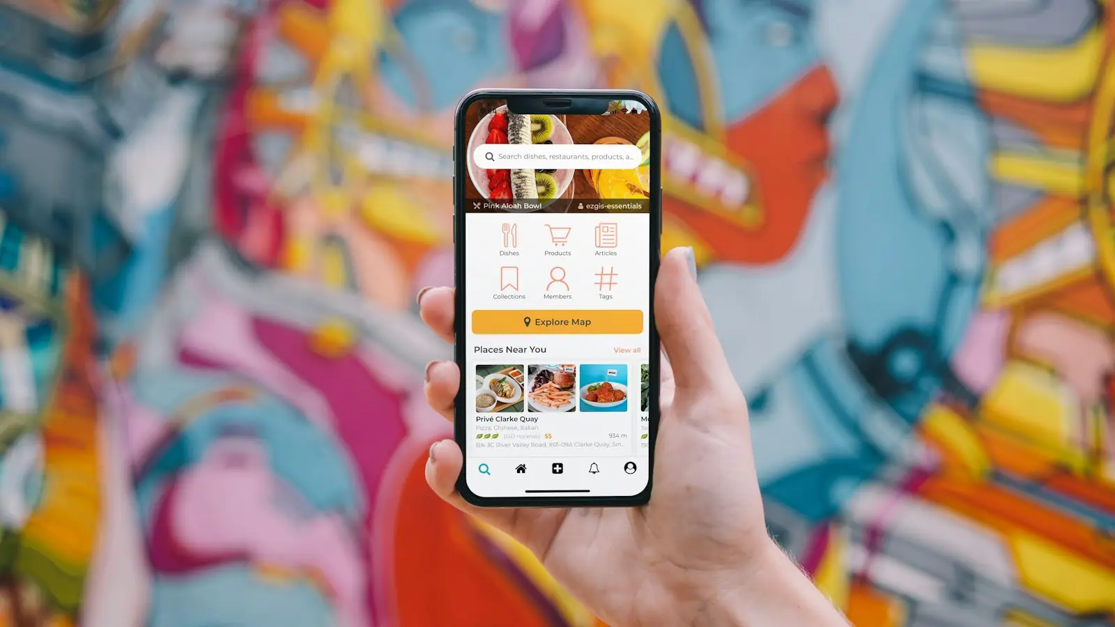 Hand holding a smartphone in front of a colourful mural